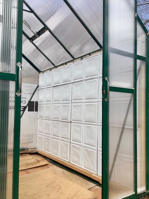 Greenhouse interior with transparent walls and a wooden floor.